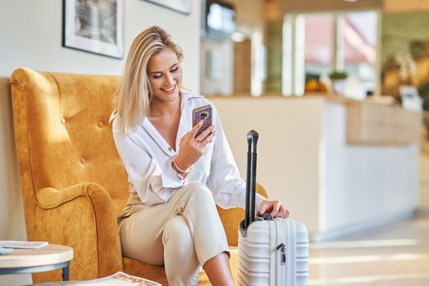 Businesswoman with white suitcase in modern hotel foyer