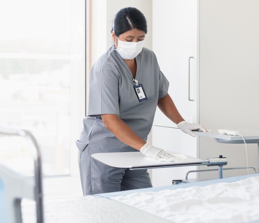 Healthcare worker sanitizing bedside table for patient