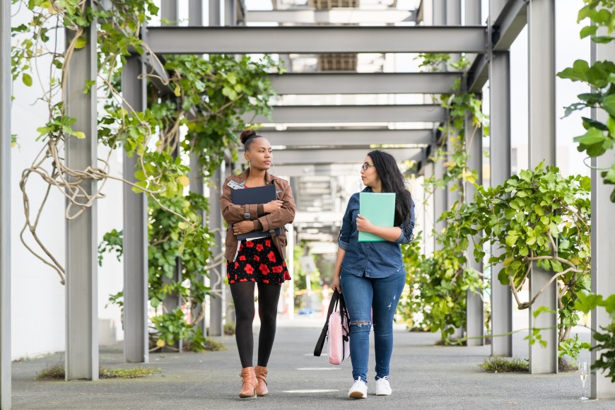 Two female students walking through university college grounds