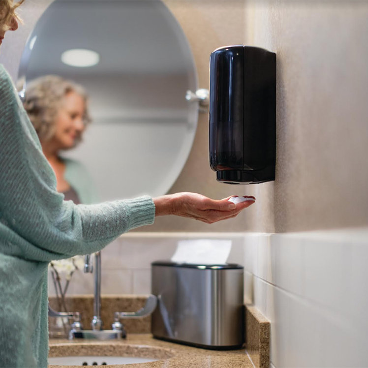 Woman with Tork touch free soap dispenser